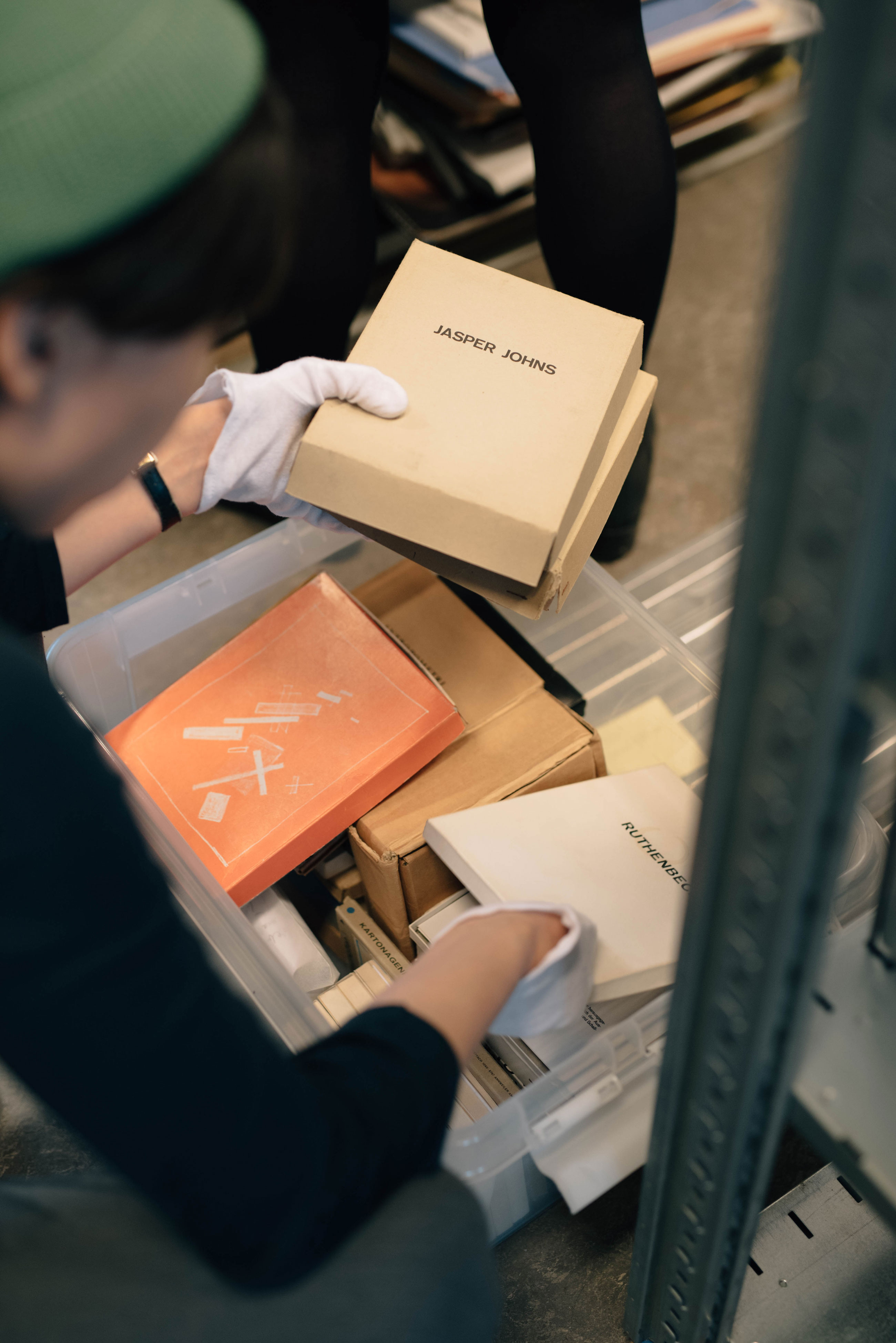 Artist Aram Lee holding a box from Jasper Johns at De Appel's archive, part of the project Landscape with Bear, curated by the De Appel Curatorial Programme.